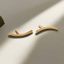  Gold curved earrings on a beige background