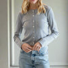 Woman wearing a gray cardigan and blue jeans against a white background