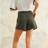 Person wearing dark denim shorts with a white background