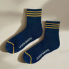 Pair of navy socks with gold stripes and 'Le Bon Shoppe' branding on a white background