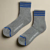 Gray socks with blue stripes and 'Le Bon Shoppe' branding on a light gray background